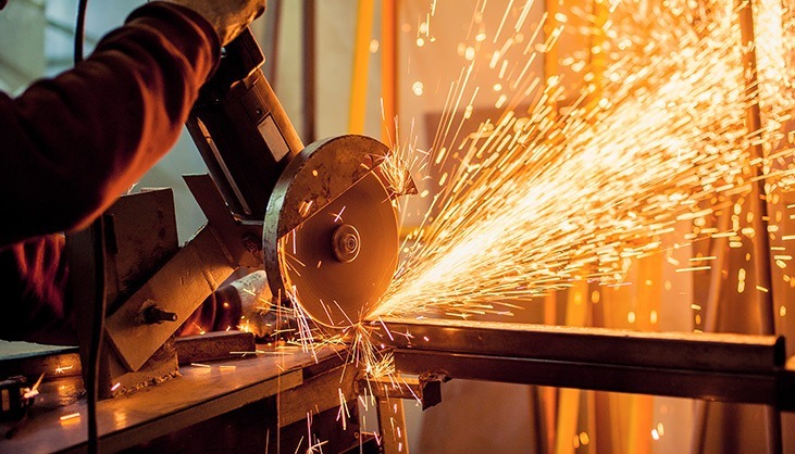 Máquina realizando corte em uma barra metálica, com faíscas